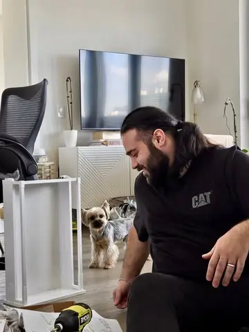 A Moving United mover assembling furniture in a condo while a small dog watches