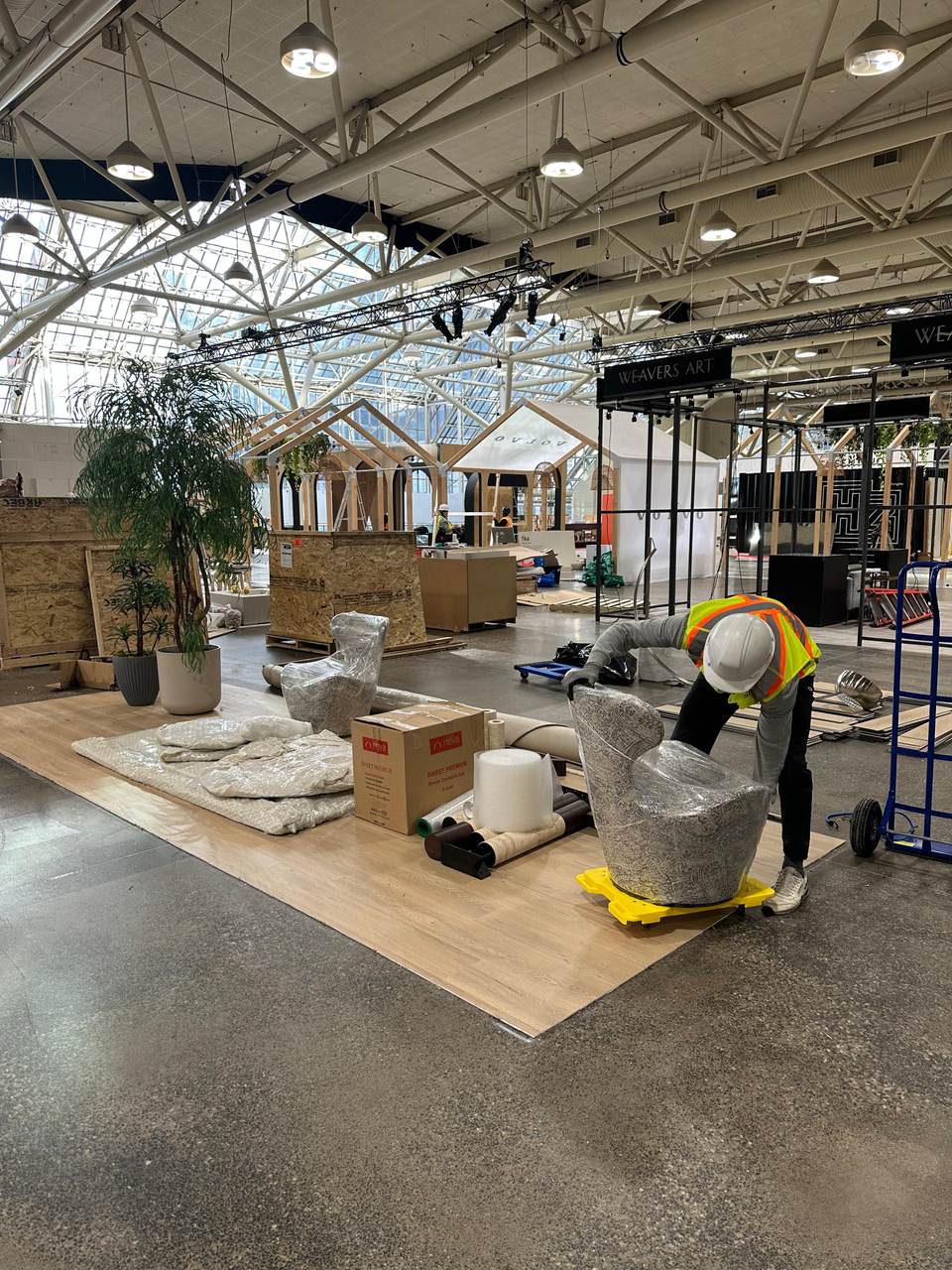 Crew member in a hard hat and safety vest unwrapping chairs on the exhibition floor of the Metro Toronto Convention Centre