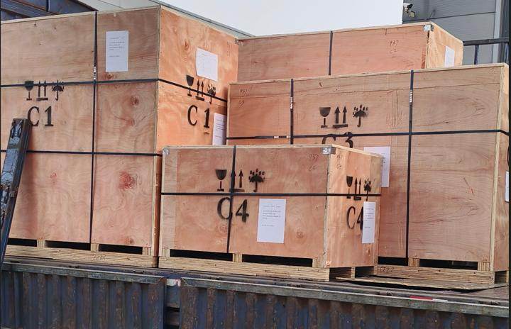 Wooden crates of windows and frames, marked with handling symbols, stacked on a shipping container
