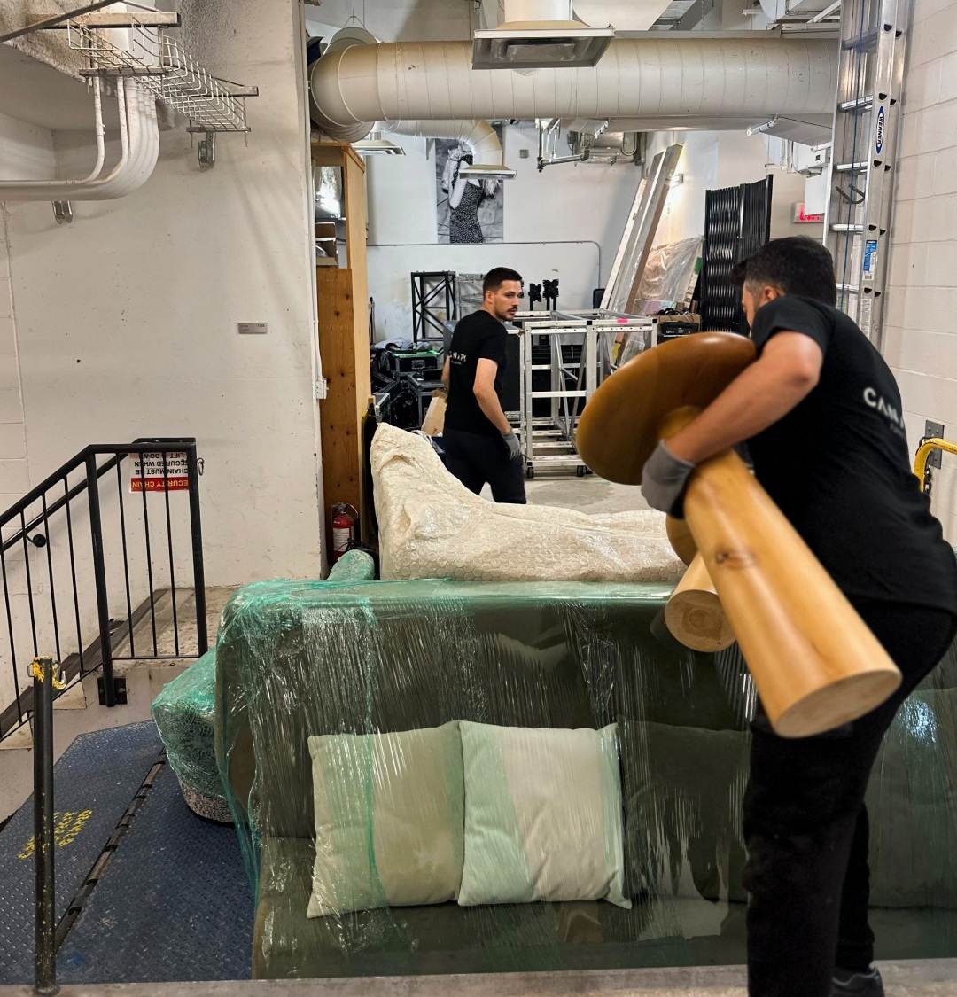 Two Moving United crew members carrying furniture into the TIFF VIP Lounge venue
